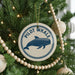 A Christmas tree decorated with ornaments, including a round ornament with a blue whale image and the text "PILOT WHALE" around the edge.