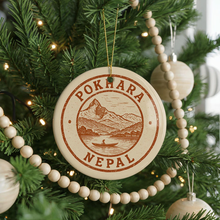 A Christmas tree decorated with ornaments, including a circular ornament with the text "POKHARA NEPAUL" and a mountain landscape design.
