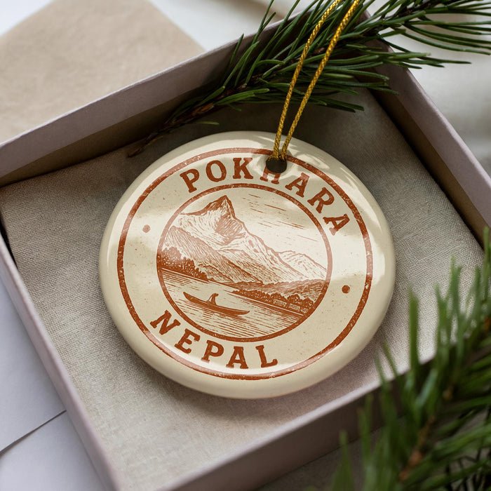 A decorative ornament with the text "POKKARA NEPAIL" printed on it, surrounded by pine branches.