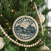 A Christmas tree decorated with ornaments, including a circular ornament with the text "PORT LOUIS MAURITIUS" and a decorative beaded string.