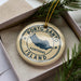 A circular ornament with the text "PORTO SANTO ISLAND" printed on it, surrounded by pine branches.