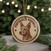 A circular ornament featuring a dog's head and the text "Portuguese Podego" is displayed in front of a blurred Christmas tree with twinkling lights.
