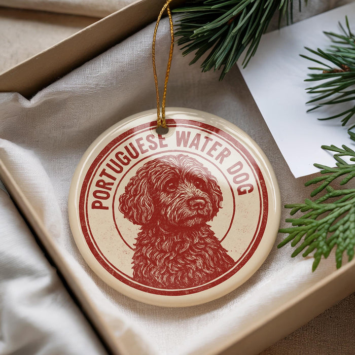 A round ornament featuring a red and white illustration of a Portuguese Water Dog dog.