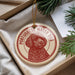 A round ornament featuring a red and white illustration of a Portuguese Water Dog dog.
