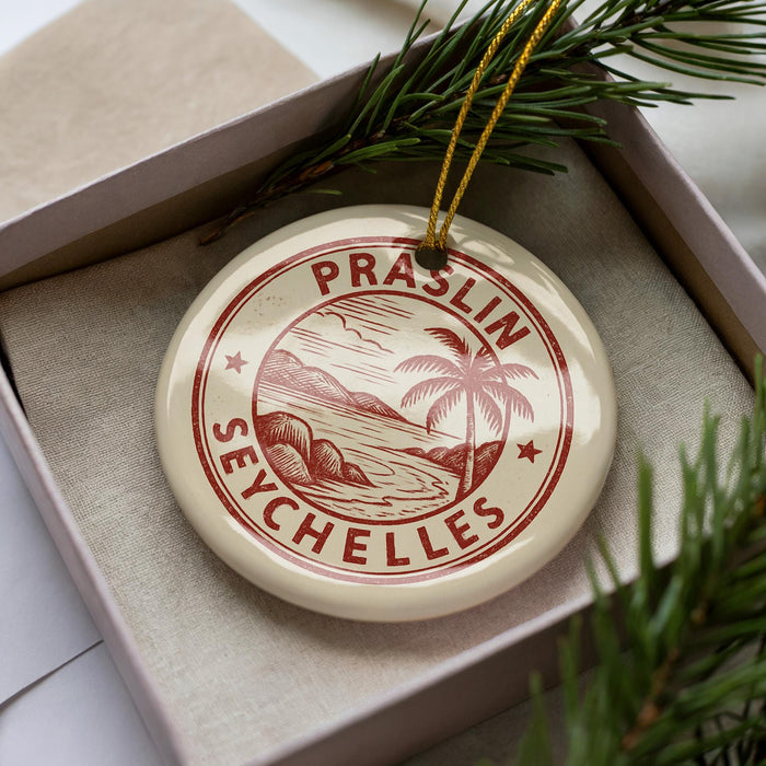 A circular ornament with the text "PRASLIN SEYCHELLES" printed on it, surrounded by pine branches.