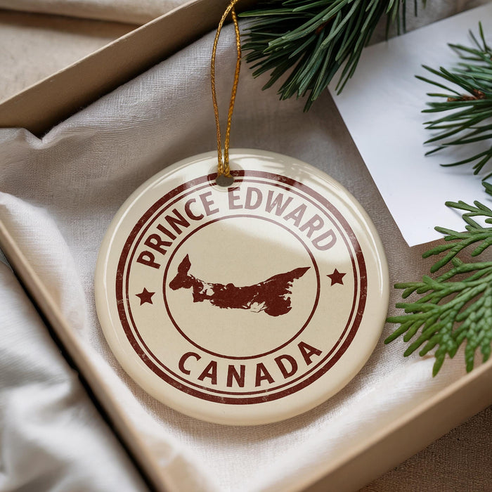 A circular ornament with the text "PRINCE EDWARD CANADA" printed on it, surrounded by pine branches.