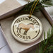 A circular ornament with a brown horse image and the text "PRZEWALSKI'S HORSE" printed on it, placed inside a box with pine branches.