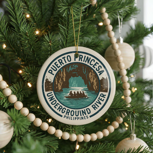 A round ornament on a Christmas tree, featuring a design of a cave with a boat in the water, surrounded by text that reads "PUERTO PRINCESA UNDERGROUND RIVER PHILIPPINES".