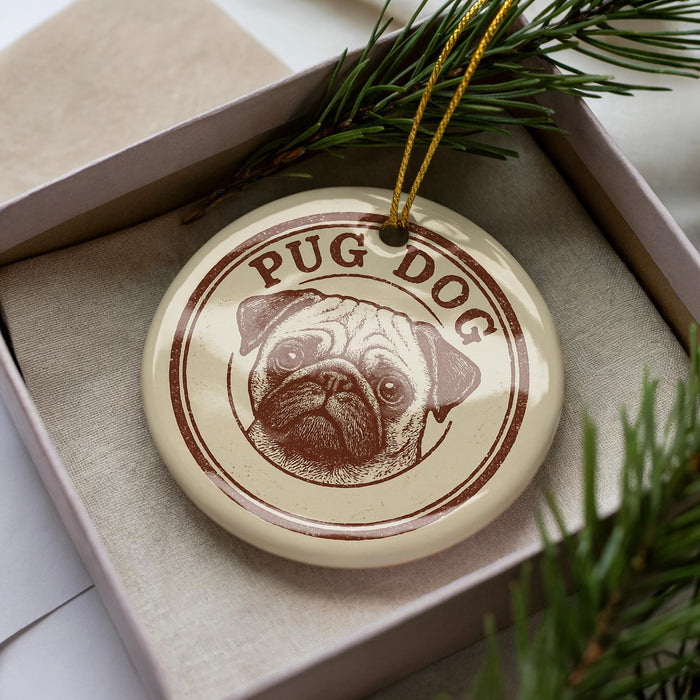 A ceramic ornament in a box, featuring a pug dog design with the text "PUG DOG" printed on it.
