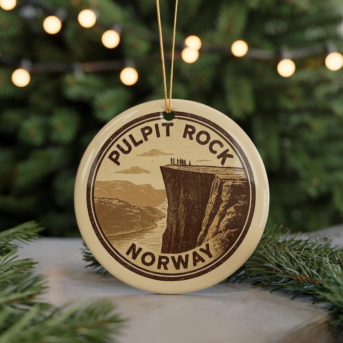 A circular ornament with the text "PULPIT ROCK NORWAY" printed on it, featuring an illustration of a cliff with people standing on the edge.