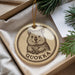 A round ornament with a cartoon image of a wombat and the word "QUOKKA" printed on it, hanging from a string.