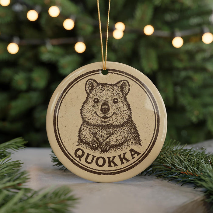 A round ornament featuring a cartoon image of a wombat, with the word "QUOKKA" written below it.