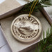A circular ornament with the text "RAIATEA FRENCH POLYNESIA" printed on it, surrounded by pine branches.