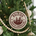 A Christmas tree decorated with ornaments, including a circular ornament with the text "RALEIGH NORTH CAROLINA" and a cityscape illustration.