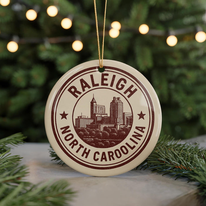 A circular ornament with the text "RALEIGH NORTH CAROLINA" and an illustration of a city skyline, hanging from a string.