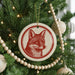 A Christmas tree decorated with ornaments, including a red and white fox ornament hanging from the tree.