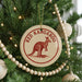 A Christmas tree decorated with ornaments, including a circular ornament with a kangaroo design and the text "RED KANGAROO" printed on it.
