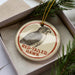 A circular ornament with a red border and a black and white illustration of a red-tailed hawk.