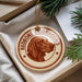A round ornament with a brown dog's head and the text "REDBONE COONHOUND" is displayed in a box, surrounded by pine branches.