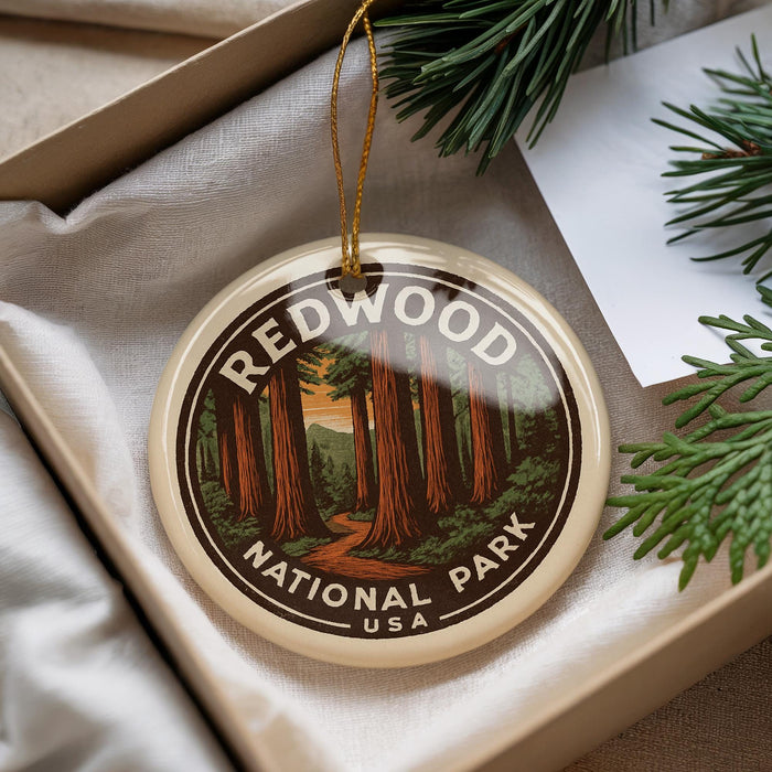 A decorative ornament with the text "REDWOOD NATIONAL PARK USA" and an illustration of a forest of tall trees, hanging from a string.
