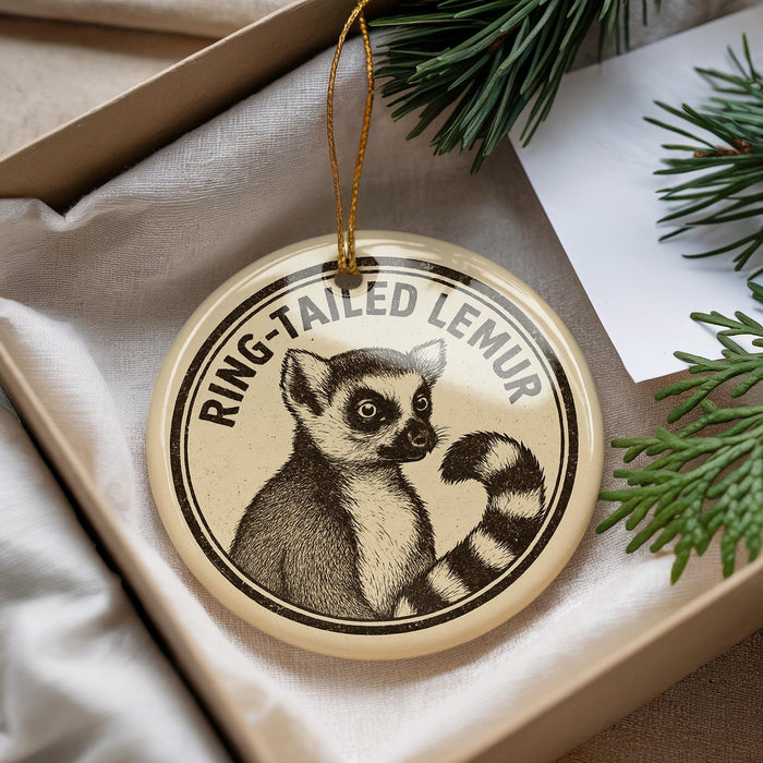 A decorative ornament featuring a lemur, a type of primate, is displayed in a box with pine branches.