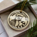 A circular ornament with a lemur image and the text "RING-TAILED LEMUR" printed on it, placed inside a box with pine branches.