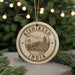 A circular ornament with the text "RISHIKESH INDIA" printed on it, featuring an illustration of a bridge and mountains.