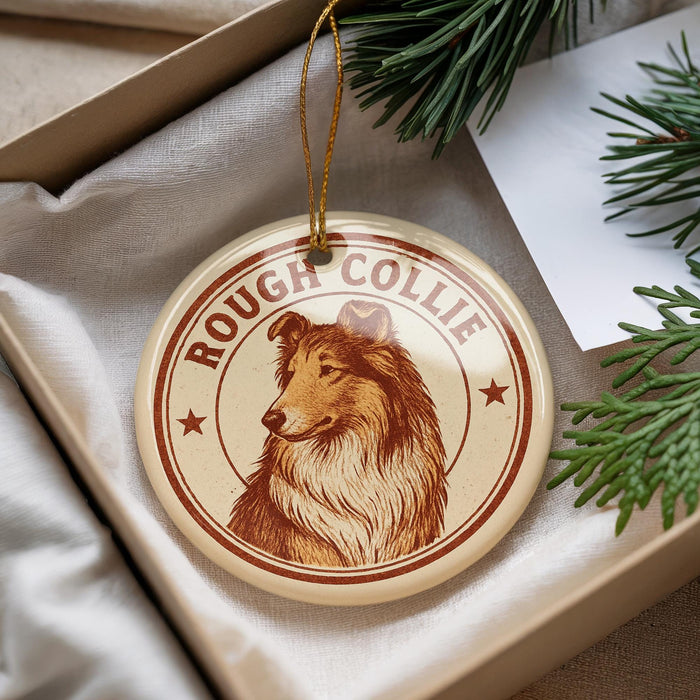 A round ornament featuring a collie dog, with the text "ROUGH COLLIE" printed on it, is displayed in a box with pine branches.