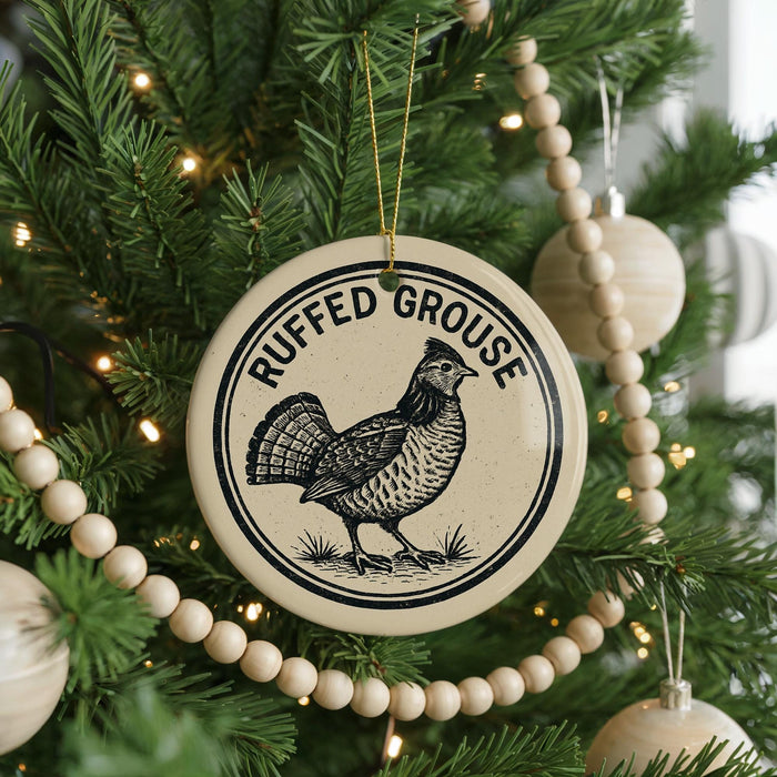 A Christmas tree decorated with ornaments, including a round ornament with a black and white illustration of a grouse and the text "RUFFED GOUSE" on it.