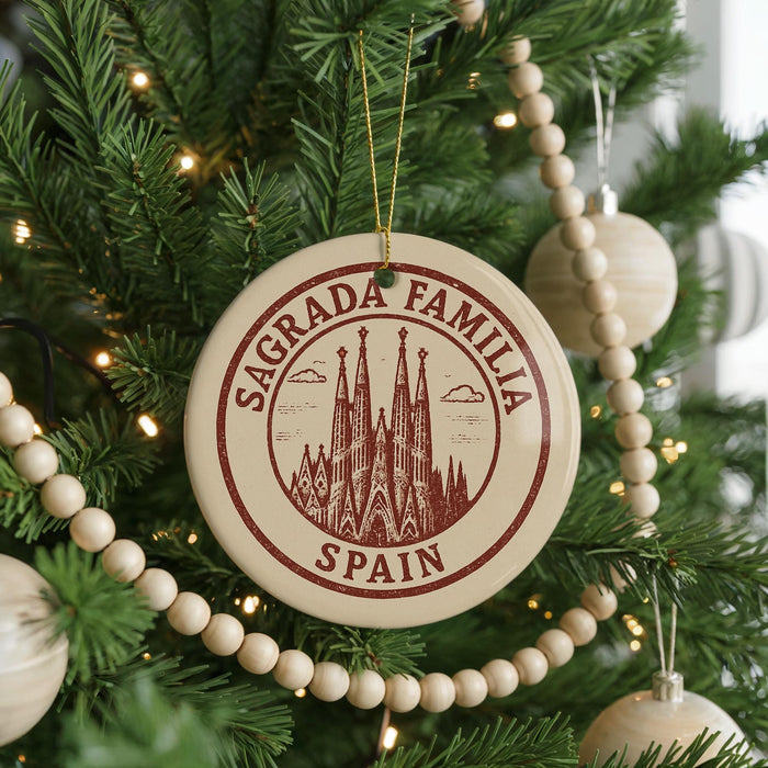 A Christmas tree decorated with ornaments, including a circular ornament with the text "Sagrada Familia" and "Spain" printed on it.