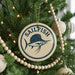 A Christmas tree decorated with ornaments, including a round ornament with a blue and white design featuring a sailfish and the word "SAILFISH" written on it.