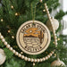 A round ornament on a Christmas tree, featuring a desert landscape with a cactus and mountains, along with the text "Salar de Uyuni Bolivia".