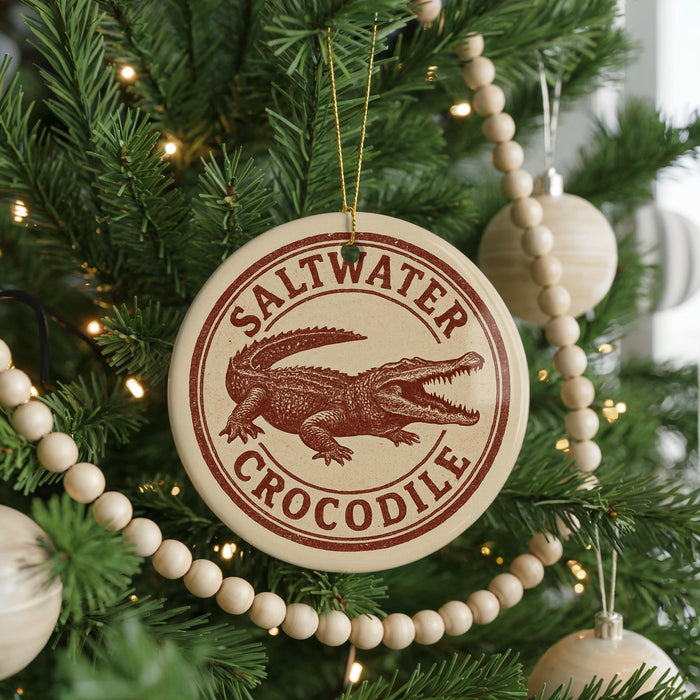 A Christmas tree decorated with ornaments, including a circular ornament with a crocodile design and the text "Saltwater Crocodile" on it.