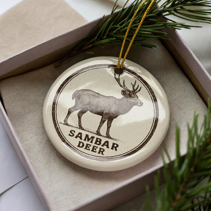 A ceramic ornament in a box, featuring a deer illustration and the text "SAMBAR DEER".
