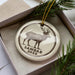 A ceramic ornament in a box, featuring a deer illustration and the text "SAMBAR DEER".