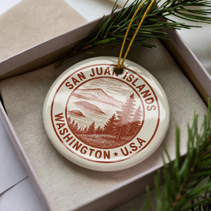 A circular ornament with a design of a mountain landscape and the text "SAN JUAN ISLANDS WASHINGTON U.S.A." hanging from a string.