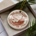 A circular ornament with a design of a mountain landscape and the text "SAN JUAN ISLANDS WASHINGTON U.S.A." hanging from a string.
