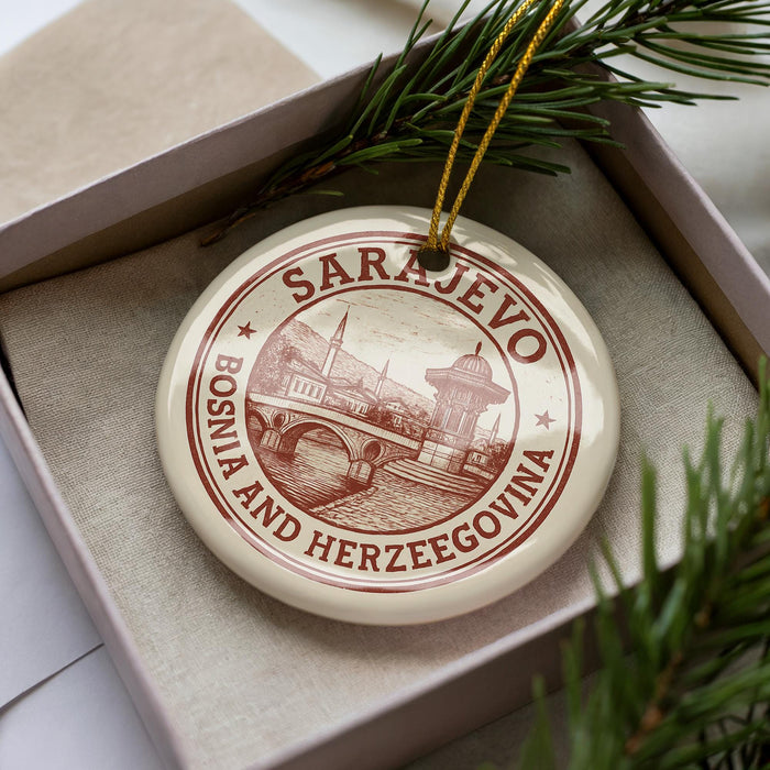 A circular ornament with the text "SARajevo, Bosnia and Herzegovina" printed on it, placed in a box with pine branches.