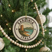 A Christmas tree decorated with ornaments, including a circular ornament with the text "SARDINIA ITALY" and a lighthouse image.