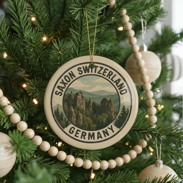 A round ornament on a Christmas tree, featuring a scenic image of Saxon Switzerland and Germany.