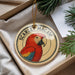 A round ornament featuring a red parrot, with the text "SCARLET MACAW" around the edge.