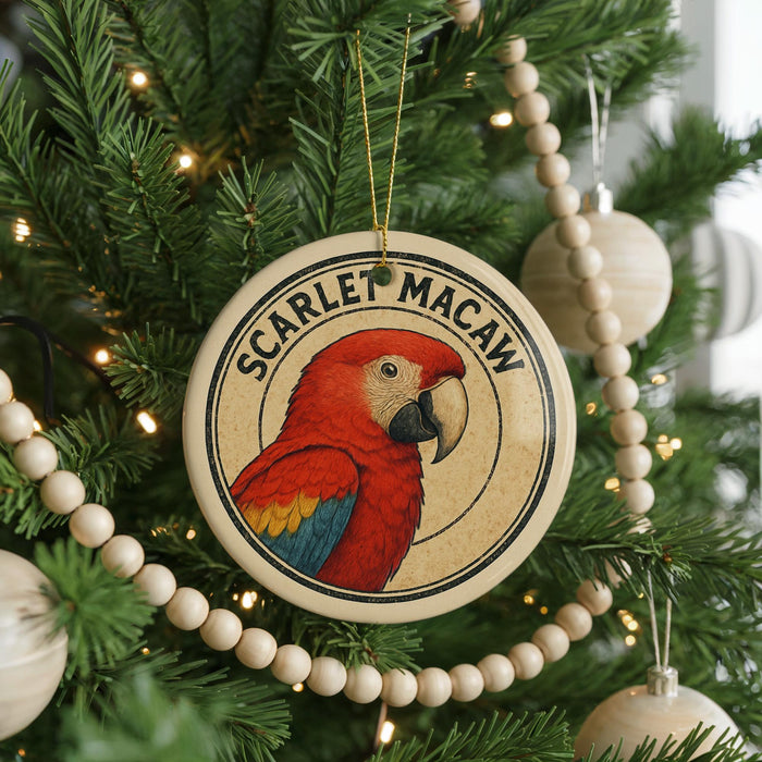 A round ornament featuring a red parrot is hanging on a Christmas tree, surrounded by lights and ornaments.