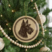 A Christmas tree decorated with ornaments, including a circular ornament featuring a silhouette of a dog's head.
