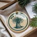 A round ornament with the text "SEA ANEMONE" printed on it, surrounded by pine branches.