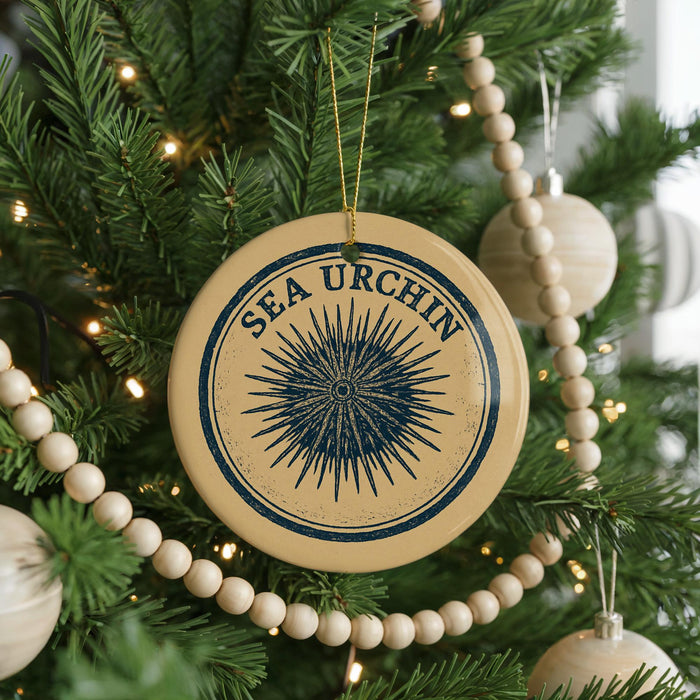 A Christmas tree decorated with ornaments, including a circular ornament with a design resembling a sea urchin and the text "SEA URCIN" on it.