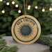 A round ornament with the text "SEA URCIN" and a graphic of a sea urchin is displayed on a table, surrounded by pine branches and twinkling lights.