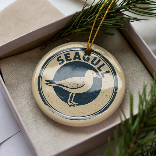 A decorative ornament in a box, featuring a seagull silhouette and the word "SEAGULL" written in a circular design.