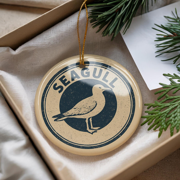 A round ornament with a bird image and the word "SEAGULL" printed on it, hanging from a string.
