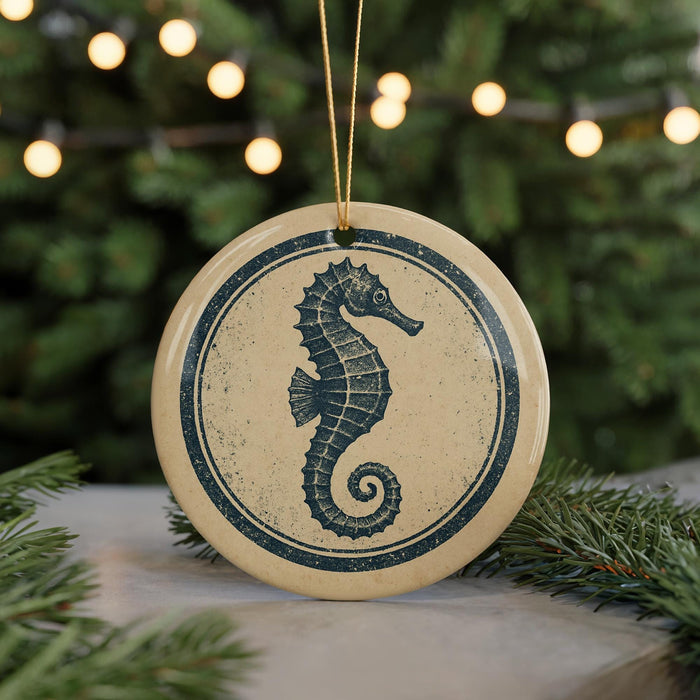 A round ornament featuring a seahorse design is displayed against a blurred background of a Christmas tree with twinkling lights.