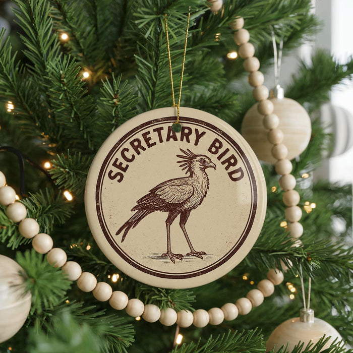 A round ornament on a Christmas tree, featuring a bird design and the text "SECRETARY BIRD".